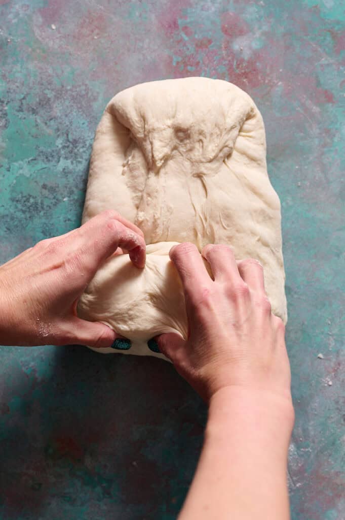 rolling up the sheet of fermented sourdough dough as a step in the shaping process