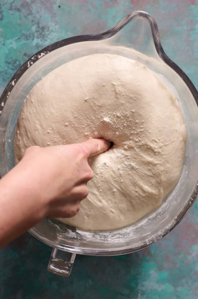 showing dough risen after bulk fermentation and using the poke test to verify proofing is done