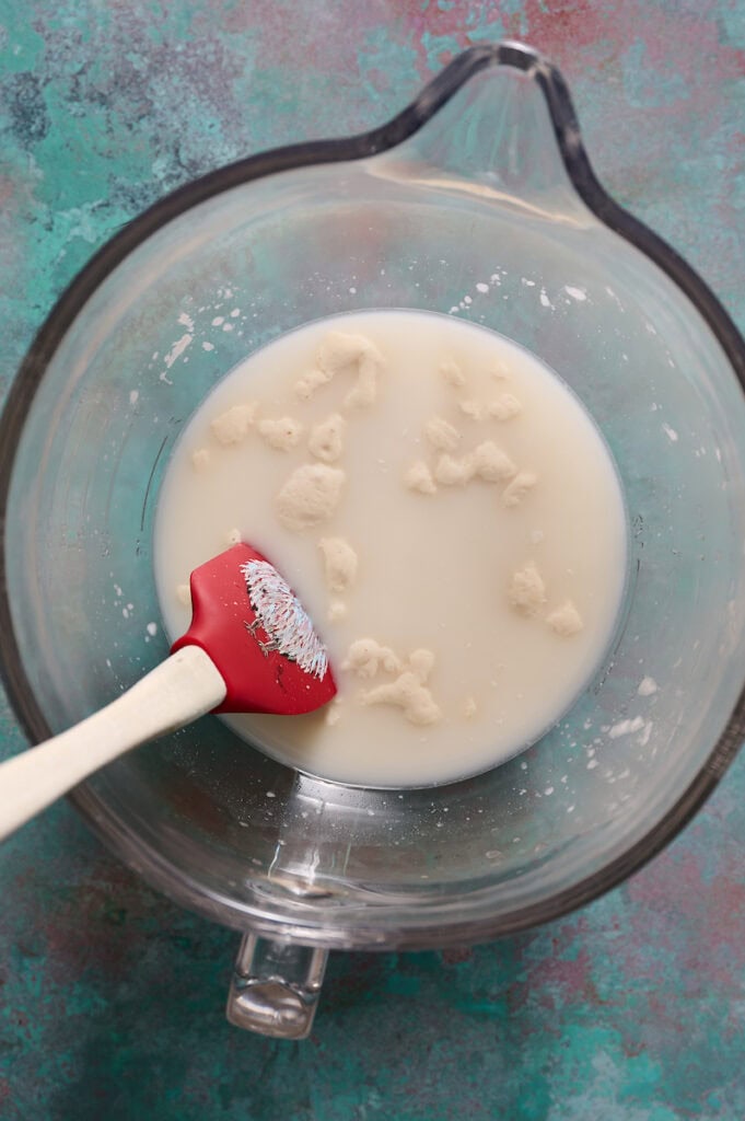 mixing peaked sourdough stater with water in a large bowl