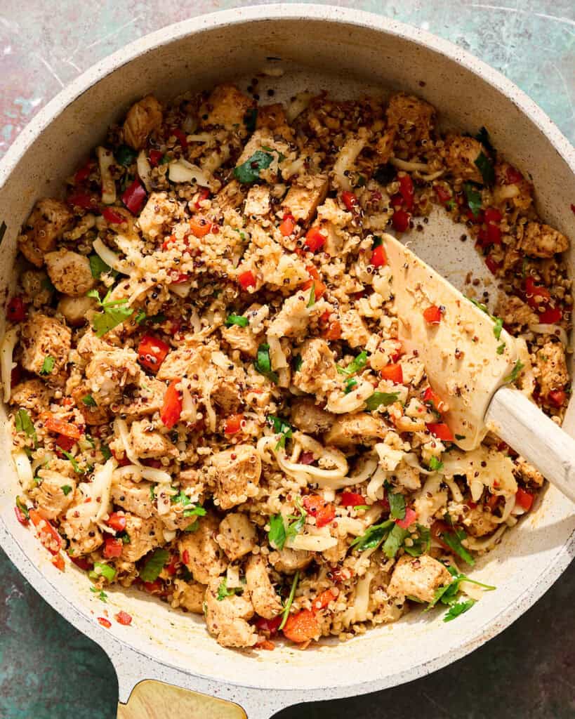 adding quinoa, cheese and cilantro to the chicken mixture in a saute pan