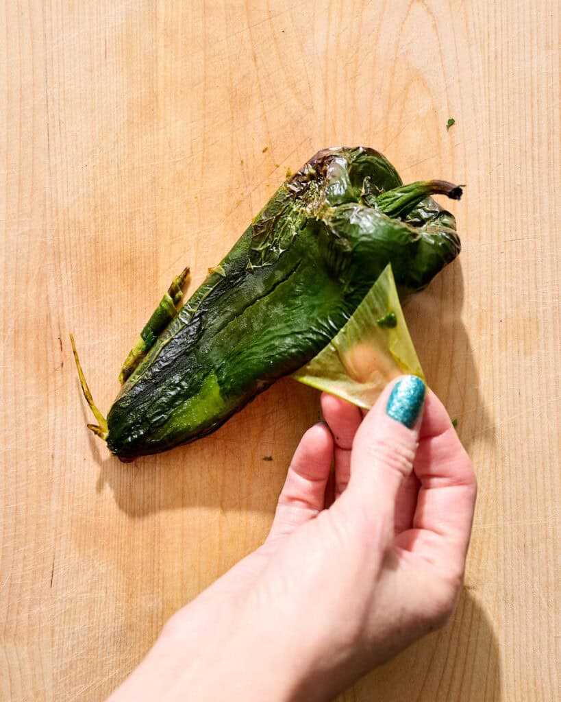 peeling the skin off the poblano pepper