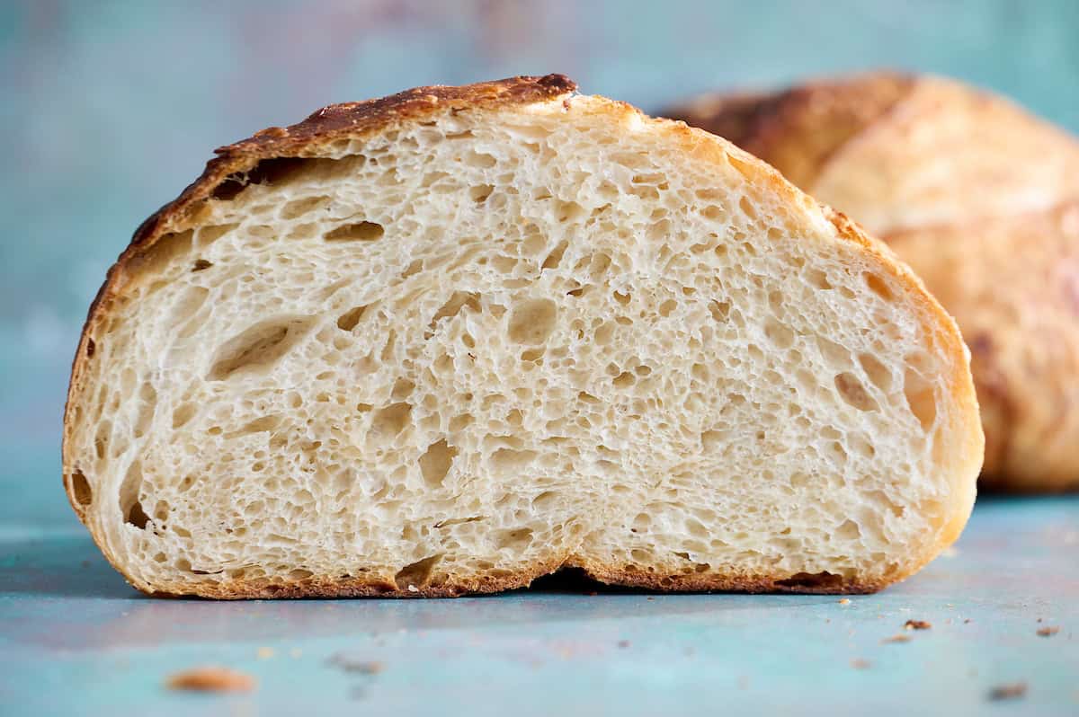 a loaf of sourdough bread sliced in half showing top and open crumb