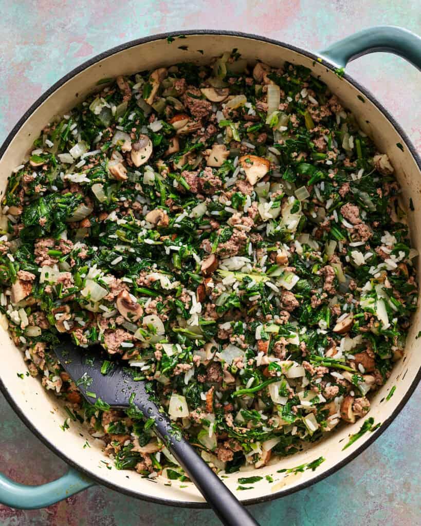 sauteed beef, onion, mushrooms and spinach in a pot