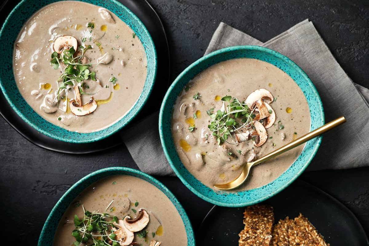 cream of mushroom soup that's vegan in a bowl with seed crackers