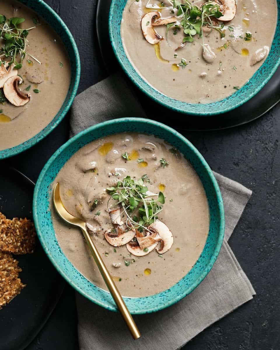 bowl of dairy free cream of mushroom soup topped with fresh mushrooms and greens