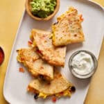 breakfast quesadillas served on a plate with greek yogurt, salsa and guac