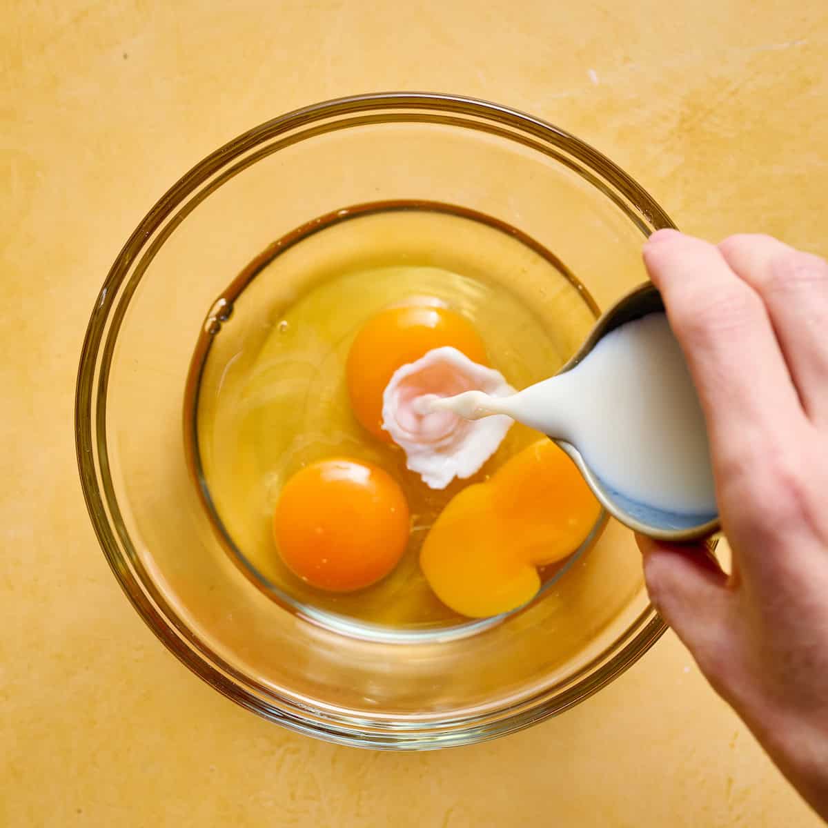 adding milk to three eggs
