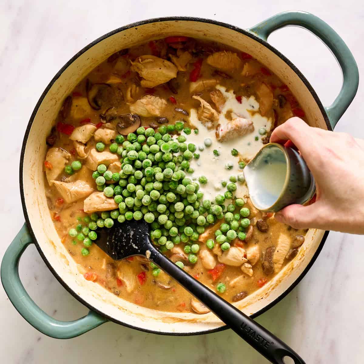 adding cream and peas to the chicken a la king