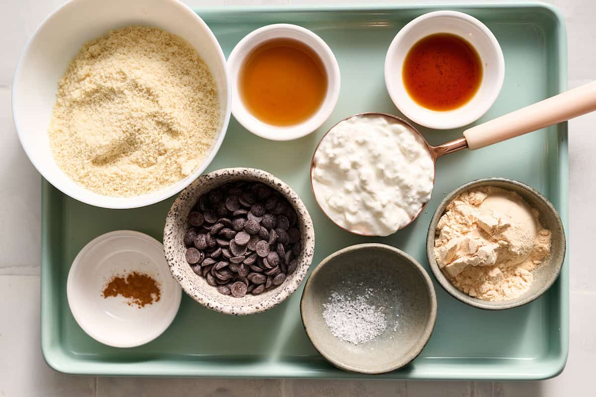 ingredients to make cottage cheese cookie dough including cottage cheese, protein powder, salt, vanilla, maple syrup, almond flour, chocolate chips and cinnamon