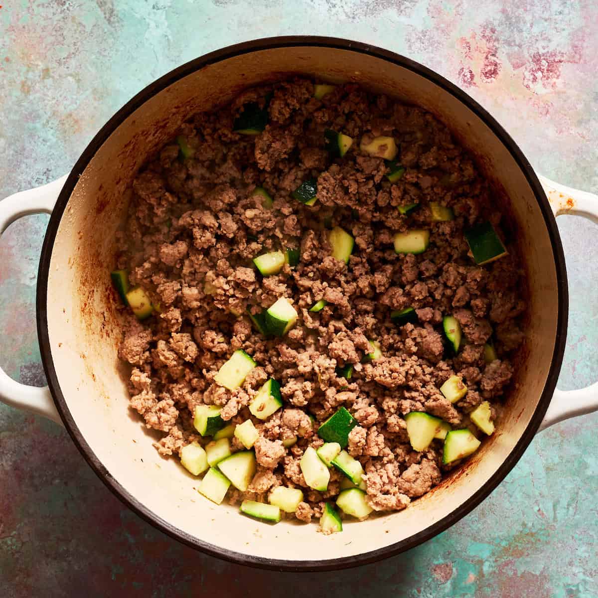 browned beef and sausage in a stock pot with zucchini added