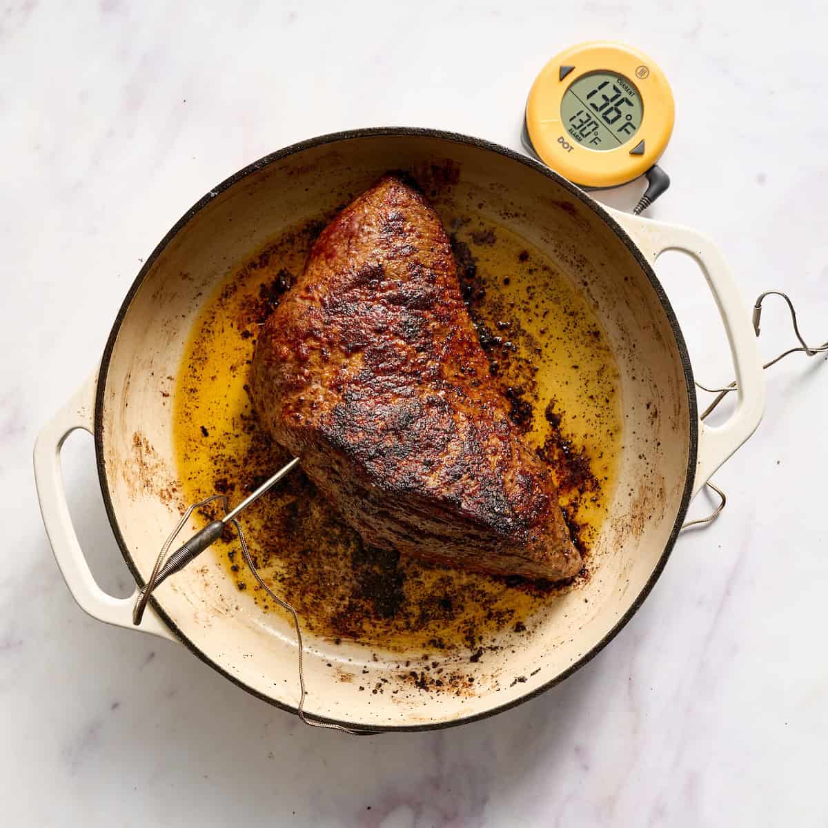 tri tip roast in a cast iron enamel pan with a probe and temp showing 136F internal temp