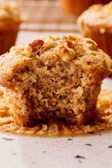 Sourdough discard banana nut muffins with golden domed tops and a bite taken out to show fluffy interior