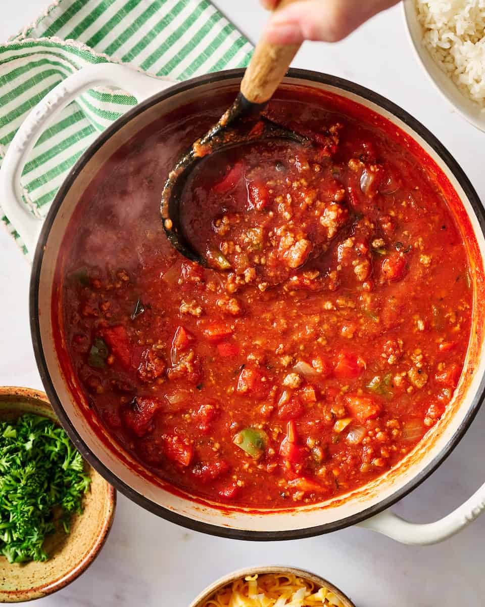 soup in a pot with steam rising and ladling out a serving