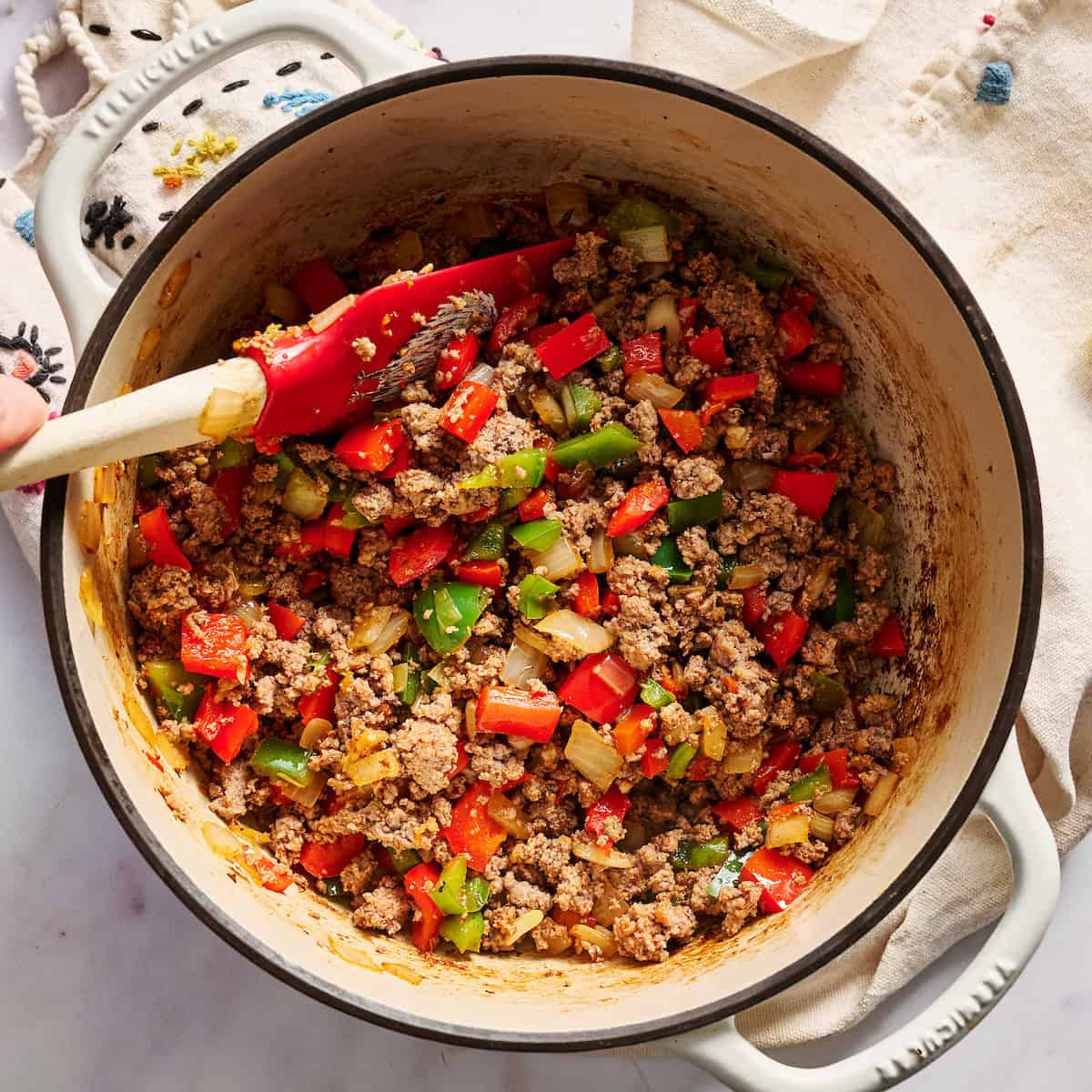 cooking peppers, spices, and beef in a dutch oven