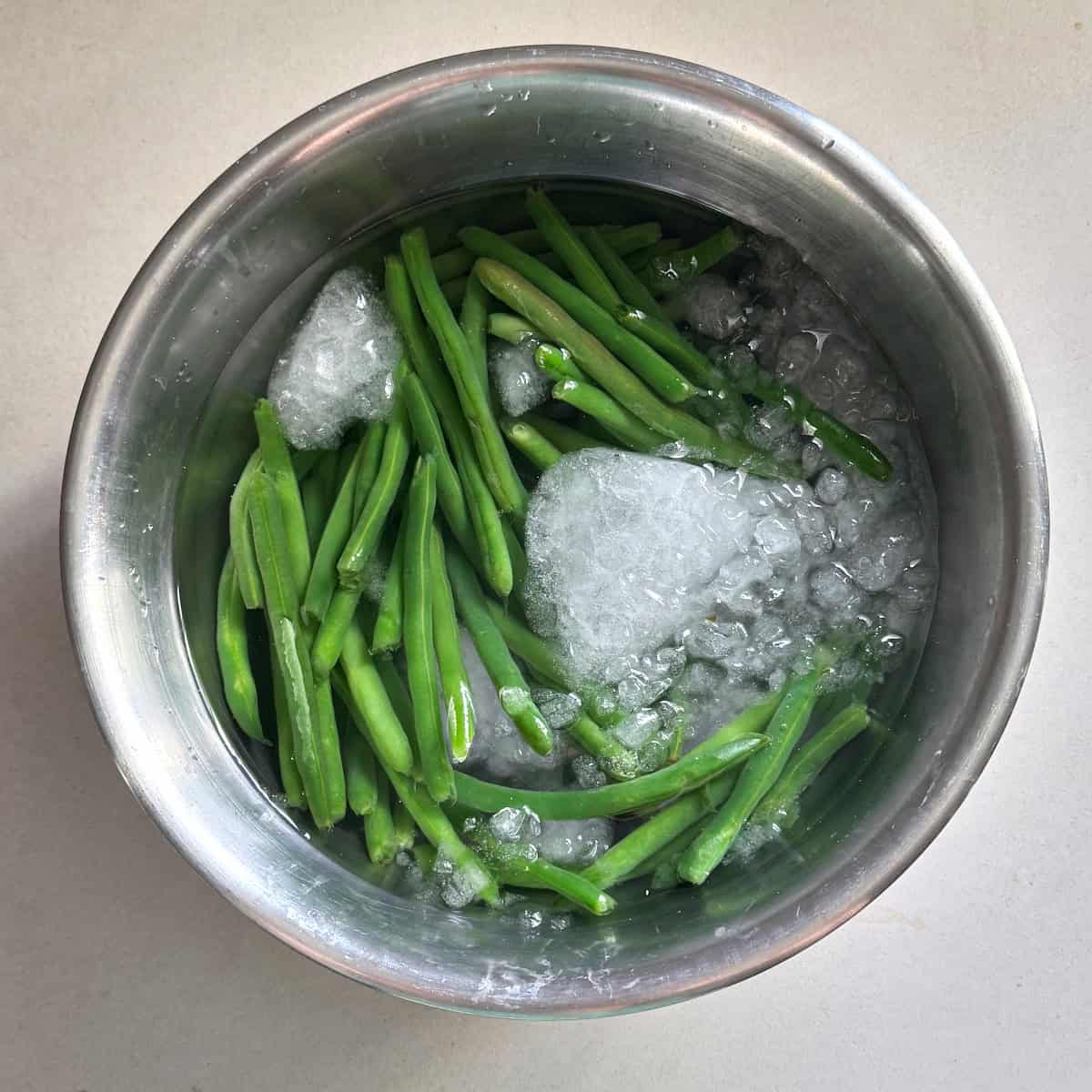 blanching the green beans in a bowl with ice