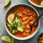 a bowl of chicken enchilada soup dressed with avocado and lime