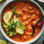 a bowl of chicken enchilada soup dressed with avocado and lime