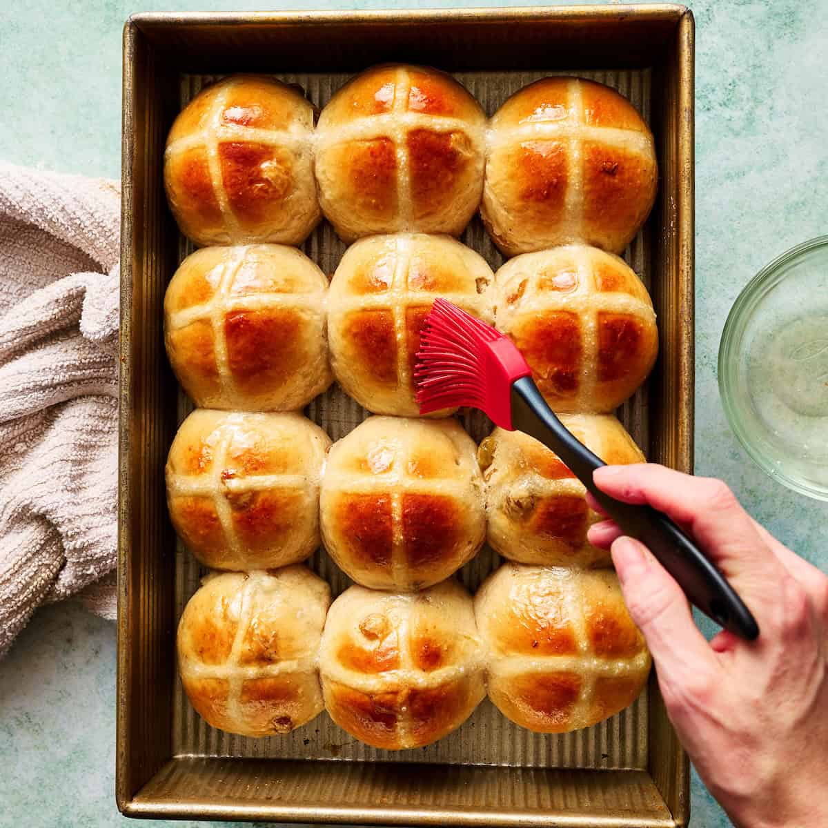 brushing glaze on baked hot cross buns