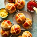 hot cross buns scattered on surface with butter and jam