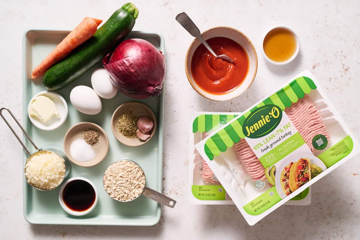ingredients to make healthy turkey meatloaf including oats, vegetables, eggs, garlic, spices, ketchup, parmesan and maple syrup