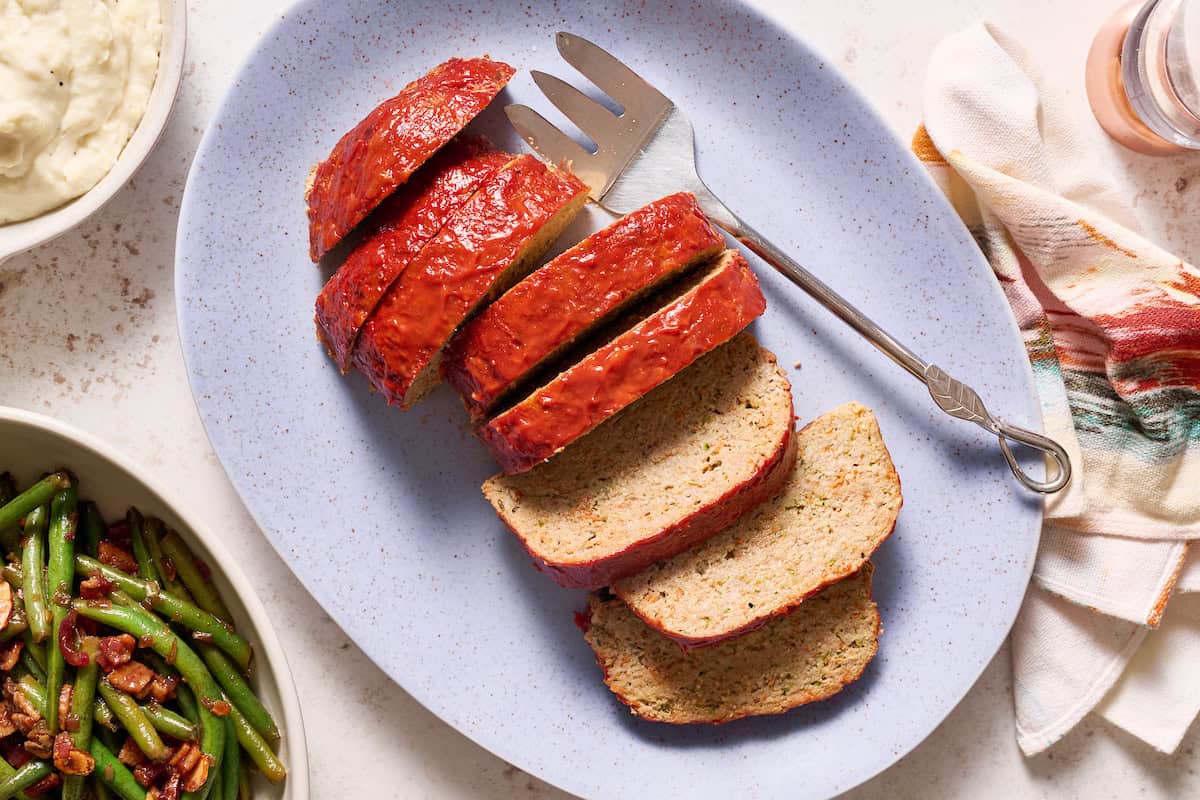 sliced turkey meatloaf served with green beans and mashed potatoes