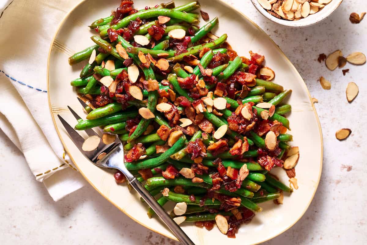 Balsamic Green Beans with Crispy Bacon and topped with toasted almonds on a serving platter