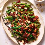 Balsamic Green Beans with Crispy Bacon and topped with toasted almonds on a serving platter