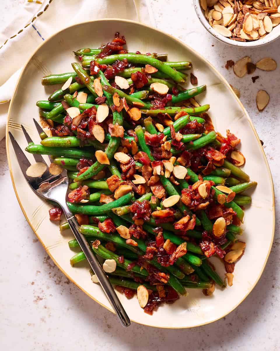 Balsamic Green Beans with Crispy Bacon and topped with toasted almonds on a serving platter
