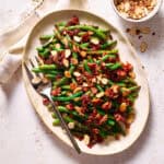 Balsamic Green Beans with Crispy Bacon and topped with toasted almonds on a serving platter