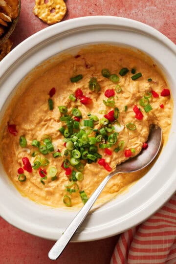 Creamy spicy buffalo chicken dip with chopped green onions and red peppers, perfect for snacks, parties.