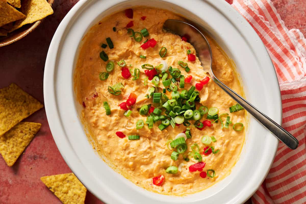 Creamy spicy buffalo chicken dip with chopped green onions and red peppers, perfect for snacks, parties.