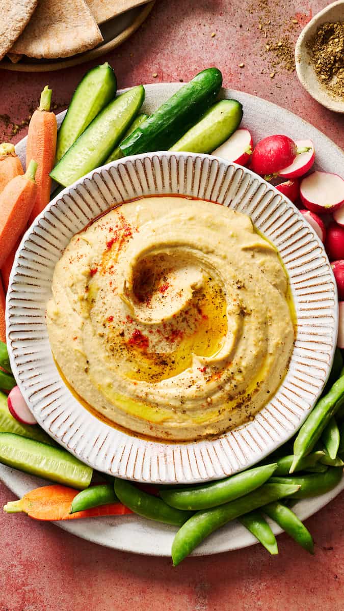 homemade hummus topped with paprika and olive oil served with veggies
