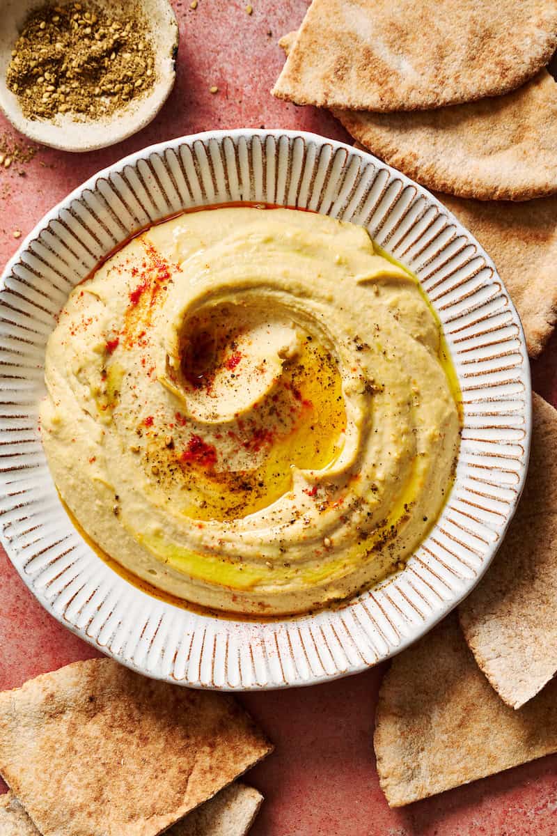homemade hummus topped with paprika and olive oil served with pita