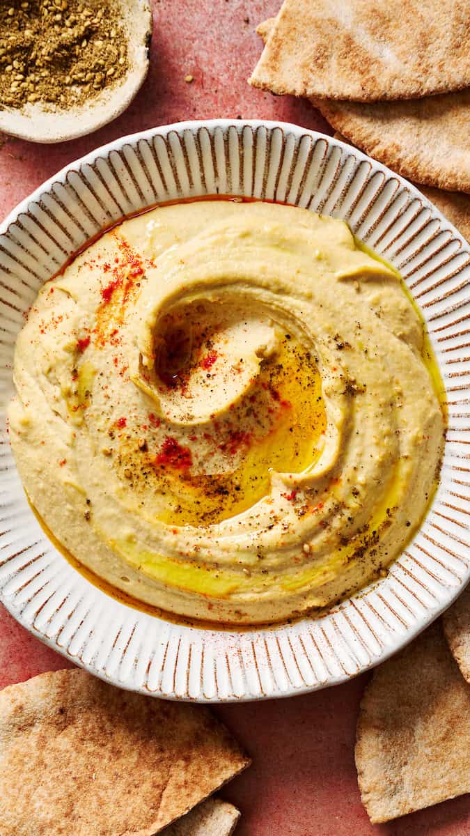 homemade hummus topped with paprika and olive oil served with pita