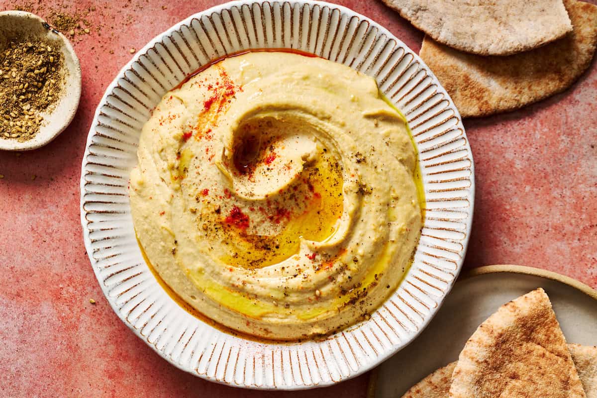 homemade hummus topped with paprika and olive oil served with pita