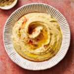 homemade hummus topped with paprika and olive oil served with pita