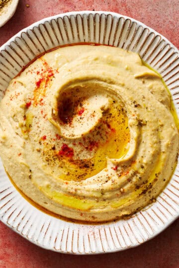 homemade hummus topped with paprika and olive oil served with pita