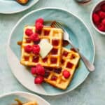 sourdough discard waffles on a plate with syrup and raspberries