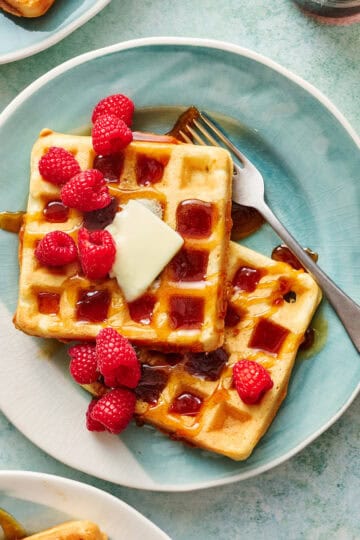 sourdough discard waffles on a plate with syrup and raspberries
