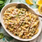Creamy Tuna pasta salad in a serving dish with lemons on the side