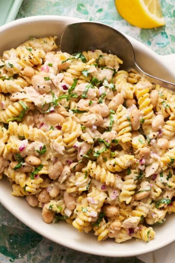 Creamy Tuna pasta salad in a serving dish with lemons on the side