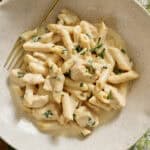 cottage cheese alfredo pasta with chicken in a bowl topped with basil