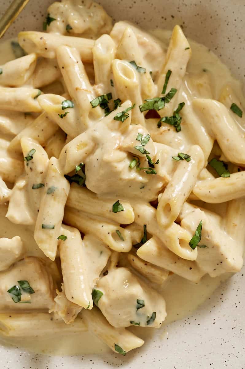 cottage cheese alfredo pasta with chicken in a bowl topped with basil