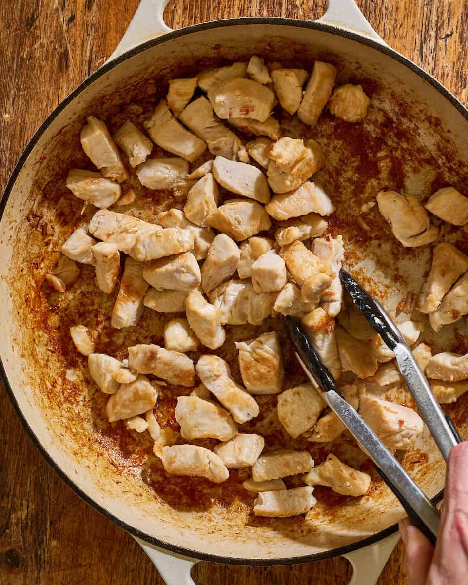 cooking seasoned chicken in a large skillet