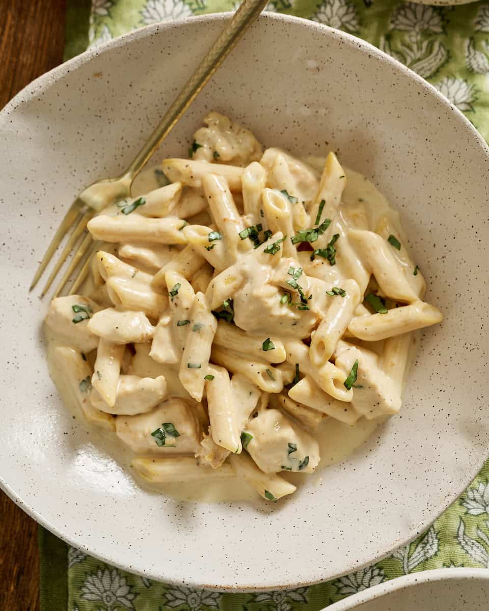 cottage cheese alfredo pasta with chicken in a bowl topped with basil