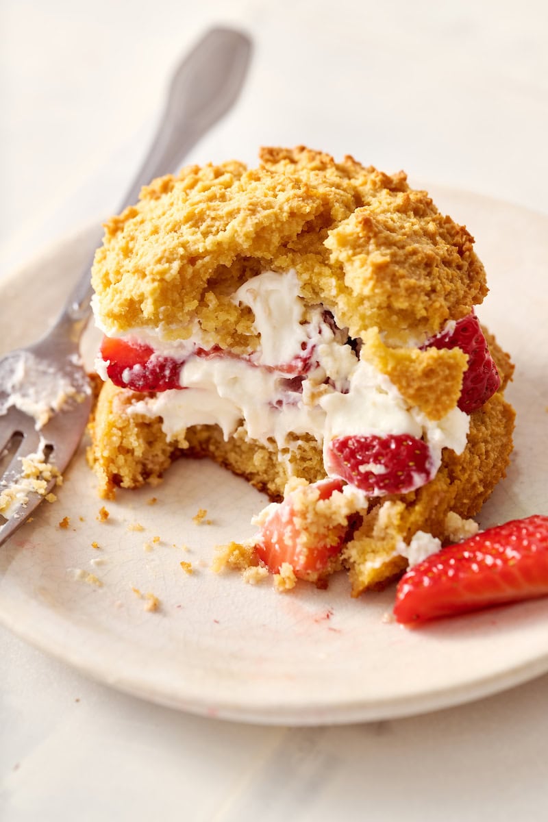 closeup of strawberry shortcakes with fresh whipped cream and a bite taken out