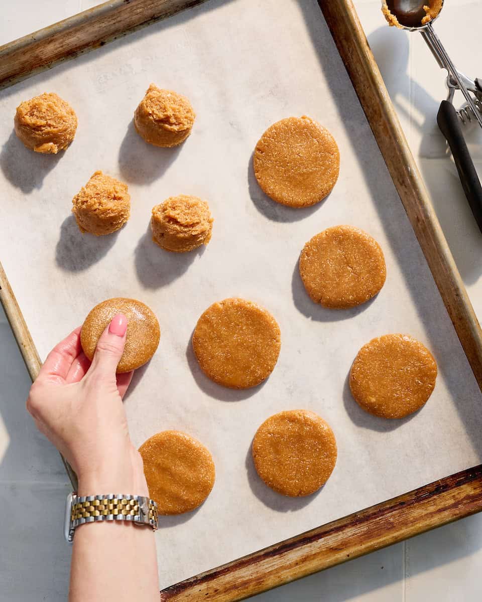 Pressing cookies into rounds on a baking sheet