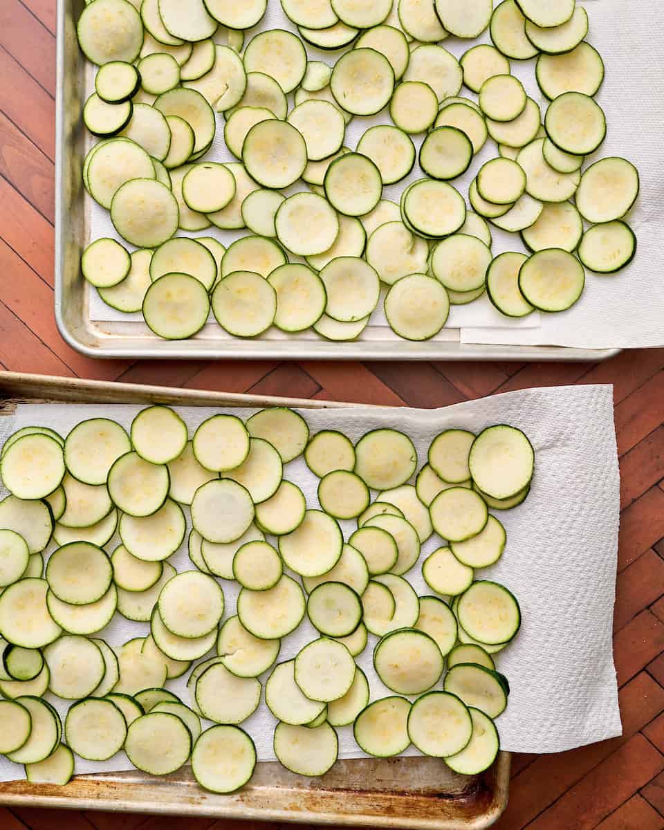 sliced zucchini coins on paper towel lined sheets