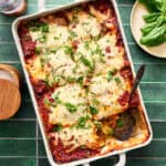 a pan of sliced zucchini lasagna topped with fresh basil
