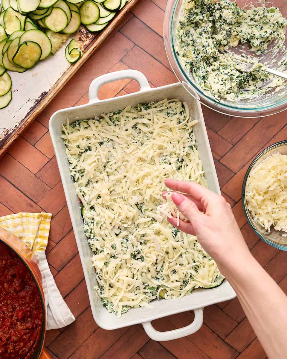 sprinkling mozzarella cheese on top of the ricotta layer